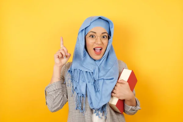 魅力的な若いイスラム教徒の女性がヒジャーブとカジュアルな服を着て 指を指して微笑んで 私はアイデアを持っている 私は答えを知っているか 解決策を知っている — ストック写真