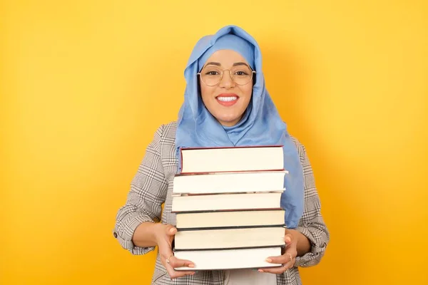 smiling young muslim woman wearing hijab with books