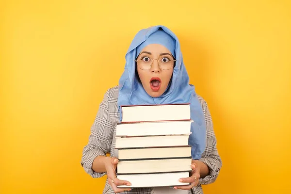 young muslim woman wearing hijab with books is confused