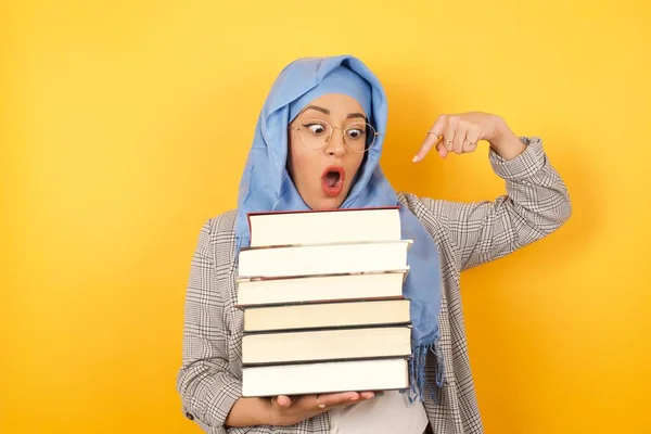 young muslim woman wearing hijab showing  books