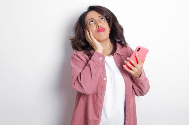 Pembe tişört giyen esmer Arap kadın ellerini yanaklarından ayırmıyor ve canı sıkkın. Stresli umutsuz model