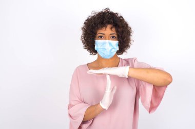 Beyaz arka planda izole edilmiş yüz maskeli genç bir kadın. Günlük kıyafetler giymiş, yüz maskesi takan genç bir kadın. Bulaşıcı hastalıklara karşı koruma.