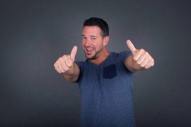 İzole edilmiş geçmişi olan yakışıklı beyaz bir adam. Elle olumlu jest yapmayı onaylıyor. Gülümsüyor ve başarı için seviniyor. Kameraya bak, kazanan jest..