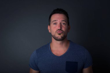 Tişört giyen hoş görünümlü, mavi gözlü, beyaz bir adam dudaklarını öpecek gibi tutuyor. Yüzü asık, mutlu bir ifade takınıyor. Kapalı yerde dikiliyorum. Güzellik konsepti.