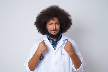  Tıp üniforması giyen genç doktor başarı ve zaferle sevinçle yumruklarını sıkıyor. Hedefe ve amaca ulaşmaktan mutlu olan şanslı adam..