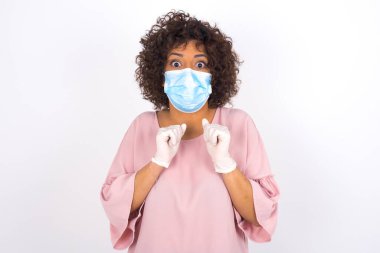 Maskeli genç bir kadın beyaz arka planda yalnız kalmaktan korkuyor. Günlük kıyafetler giymiş, yüz maskesi takan genç bir kadın. Bulaşıcı hastalıklara karşı koruma.