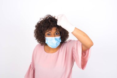 Yüzü maskeli genç bir kadın beyaz arka planda izole edilmiş. Günlük kıyafetler giymiş, yüz maskesi takan genç bir kadın. Bulaşıcı hastalıklara karşı koruma.