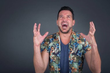 Çığlık, nefret, öfke. Mavi stüdyo arka planında ağlayan duygusal sinirli adam. Duygusal, genç yüz. Yarım boy kadın portresi. İnsani duygular, yüz ifadesi kavramı. Moda renkleri