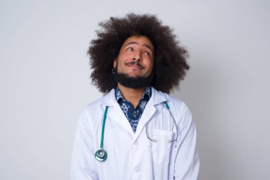 Tıp üniforması giyen çekici bir doktorun esrarengiz bir gülümsemeyle yukarı baktığı portresi..