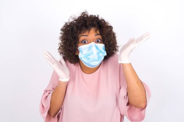 Maskeli genç bir kadın beyaz arka planda izole edilmiş. Bulaşıcı hastalıklara karşı koruma. Stüdyoda poz veren günlük kıyafetler giyen genç bir kadın.