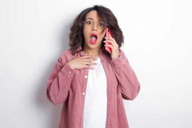 Pembe tişört giyen gülümseyen genç Latin kadın cep telefonuyla konuşuyor, hoş sohbetlerden hoşlanıyor. İnsanlar, teknoloji, iletişim konsepti