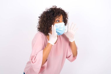 Beyaz arka planda soyutlanmış yüz maskeli genç bir kadın. Bulaşıcı hastalıklara karşı koruma. Gündelik kıyafetler giymiş genç bir kadın.