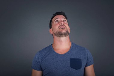 Esrarengiz bir gülümsemeyle yukarı bakan, düz saçlı, gizemli beyaz bir adamın portresi. Yakışıklı, gülümseyen çocuk gri duvara bakıyor..