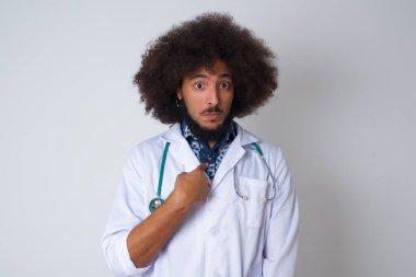 Tıp üniformalı genç bir doktorun sersemlemiş bir şekilde kendini işaret ederek 