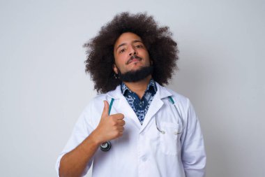 İyi iş! Mutlu gülümseyen genç bir doktorun portresi. Tıp üniforması giyen, dışarıda dikilerek el hareketi yapan genç bir doktor. Olumlu insani duygu yüz ifadesi vücut dili. Komik kız.