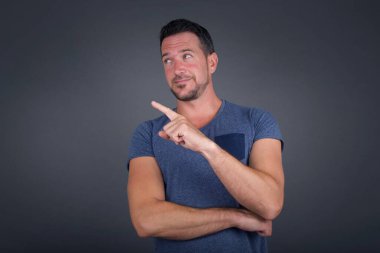 Kamerada poz veren genç bir adamın portresi hileli bir bakış ve yana hareket. Erkek tasarımcı güzel ürünleri işaret parmağıyla sunuyor. Hareket kavramı.