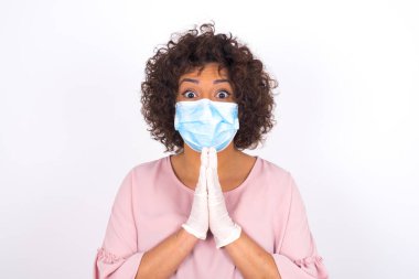 Maskeli genç bir kadın beyaz arka planda izole edilmiş olduğunu söylüyor. Bulaşıcı hastalıklara karşı koruma. Stüdyoda poz veren günlük kıyafetler giyen genç bir kadın.