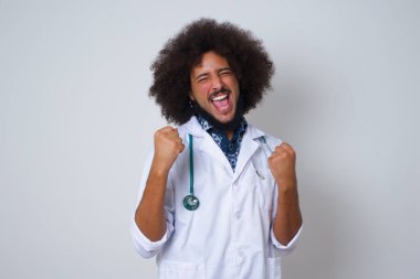  Afrikalı Amerikalı doktor onun başarısını ve zaferini sevinçle kutluyor ve yumruklarını zevkle sıkıyor. Hedefe ve hedeflere ulaşmaktan mutlu olan şanslı bir adam. Olumlu duygular, duygular.