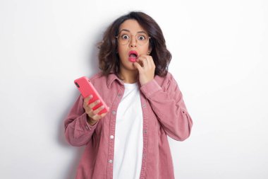 Dilsiz, esmer, pembe gömlek giyen Arap kadın ellerini açık tutuyor. Ağzı açık, şok edici haberlere tepki veriyor. Kameraya şaşkın şaşkın bakıyor.