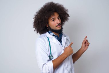 Sağlık üniforması giyen, tıbbi üniforma giyen doktor promosyon metniniz veya ilanınız için ön parmağınızla boş fotokopi alanına işaret ediyor..