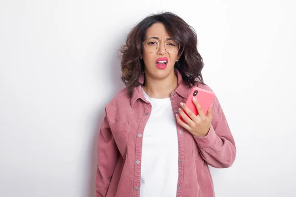 Portrait of dissatisfied woman smirks face, purses lips and looks with annoyance at camera, discontent hearing something unpleasant