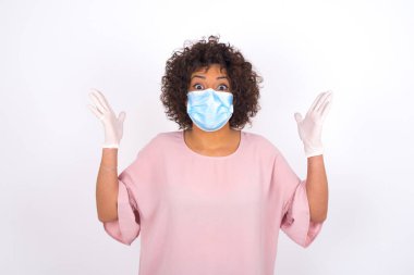 Maskeli genç bir kadın beyaz arka planda izole edilmiş. Bulaşıcı hastalıklara karşı koruma. Stüdyoda poz veren günlük kıyafetler giyen genç bir kadın.