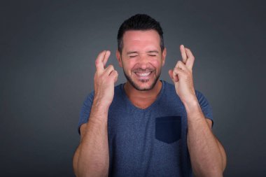 Kazanmak zorundayım. Tişört giyen neşeli esmer beyaz adam dişlerini sıkıyor, parmaklarını kaldırıyor, arzulanan dileklerde bulunuyor, yuvarlak gözlük takıyor ve sıradan kıyafetler giyiyor, iyi haberleri bekliyor, gri duvarın üzerinde duruyor.