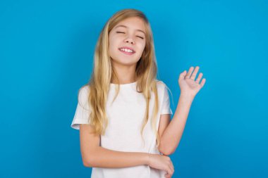 Overjoyed successful beautiful caucasian girl wearing t-shirt  raises palm and closes eyes in joy being entertained by friends clipart