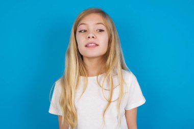 Tişört giyen güzel beyaz kız yüzünü buruşturuyor ve haç çıkartıyor. Gözleri oyuyor..