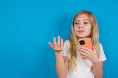 Mutlu, mutlu, beyaz tişört giyen güzel bir kız avuç içi kaldırıyor ve cep telefonunu cep telefonuyla mesajlaşma veya video görüşmeleri için yüksek hızlı internet kullanıyor.