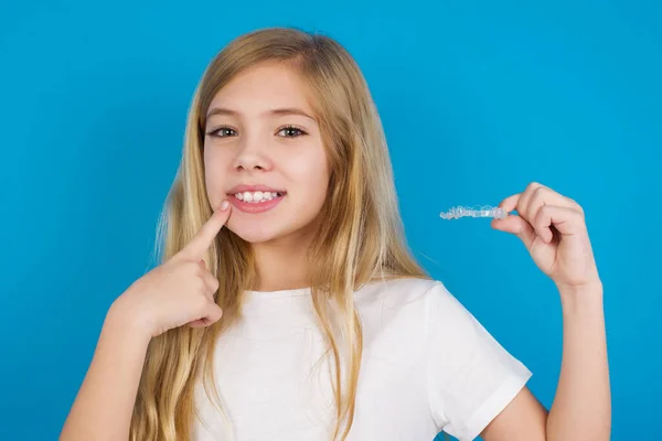 見えない外国人を抱えたTシャツを着て 彼女の完璧なまっすぐな歯を指差している美しい白人少女 歯科医療と自信のコンセプト — ストック写真