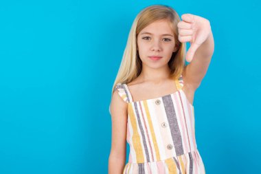 Hoşnutsuz, güzel, beyaz bir kız elbise giyer, tasvip etmez, baş parmağını aşağıda tutar, hoşlanmadığını ifade eder, hoşnutsuzca kaşlarını çatar. Olumsuz duygular.