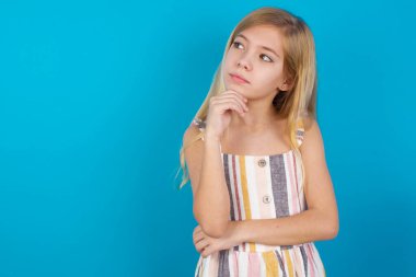 Yüz ifadeleri ve duygular. Düşünceli, güzel, beyaz bir kız. Elbise giymiş, kafasının altında el ele tutuşmuş. Şüpheli bir bakışı var..