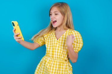 Mutlu, güzel beyaz kız e-posta ile iyi haberler alıyor ve ayakta durup cep telefonuna bakarken başarıyı kutluyor..