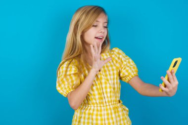 Mutlu arkadaş canlısı beyaz kız portresi elbise giyiyor selfie çekiyor ve el sallıyor, video görüşmesinde iletişim kuruyor, internette sohbet ediyor..