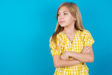 Düşünceli, düşünceli, beyaz elbiseli, kollarını kavuşturmuş, düşünceli, güzel bir kız ne yapacağını düşünüyor.