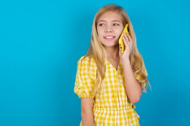 Hoş görünümlü, mutlu, beyaz elbiseli güzel bir kız. Güzel bir telefon görüşmesi yapıyor ve yan yana bakıyor. Cep telefonuyla konuşurken güzel bir havası var ve gülümsüyor.