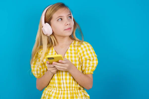 携帯電話を使用してイヤホンで音楽を聴く幸せな美しい白人少女 — ストック写真