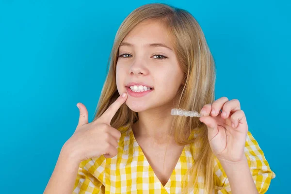 美丽的高加索女孩穿着礼服 手里拿着隐形眼镜 指着她完美的直齿 牙科保健和信心概念 — 图库照片