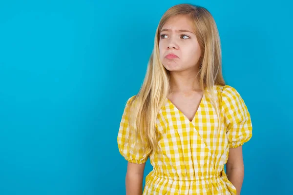 Dissatisfied girl purses lips and has unhappy expression looks away stands offended. Depressed frustrated model.