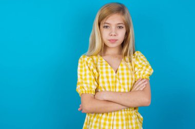 Kollarını kavuşturup kameraya bakan kendine güvenen beyaz elbiseli güzel bir kız.