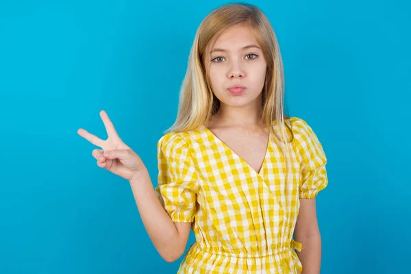 girl   makes peace gesture keeps lips folded shows v sign. Body language concept