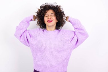 Güçlü güçlü, dişlek gülümseyen, kollarını kaldırıp pazılarını gösteren Latin bir kadın. Kaslarıma bak.!