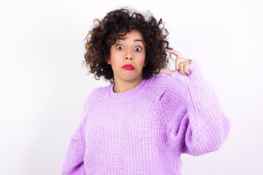  Süveter giyen, dudak büken ve el hareketleriyle hareket eden Latin bir kadın çok küçük bir şey gösteriyor..