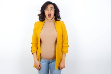 Duygusal açıdan çekici, ağzı açık hamile bir kadın büyük bir şaşkınlık ve korku içinde kameraya bakıyor. Beklenmedik haberler ve insani tepkiler.