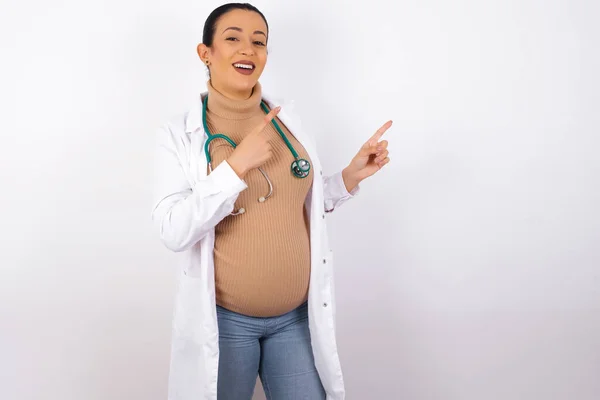 Mujer Doctora Embarazada Con Expresión Positiva Indica Con Dedo Índice —  Fotos de Stock