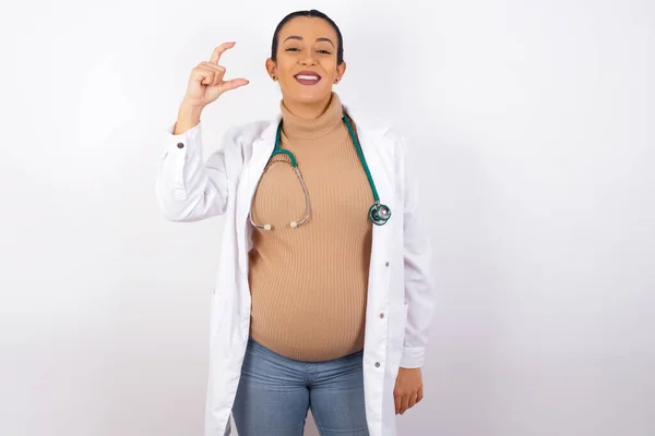 Těhotný Lékař Žena Usmívá Gestikuluje Rukou Malé Velikosti Symbol Míry — Stock fotografie