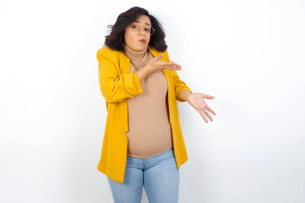 黄色いブレザーを着た妊婦は 両手を脇に置いて 奇妙なものを見せて こう言いました これが何なのか分からない 広告コンセプト — ストック写真