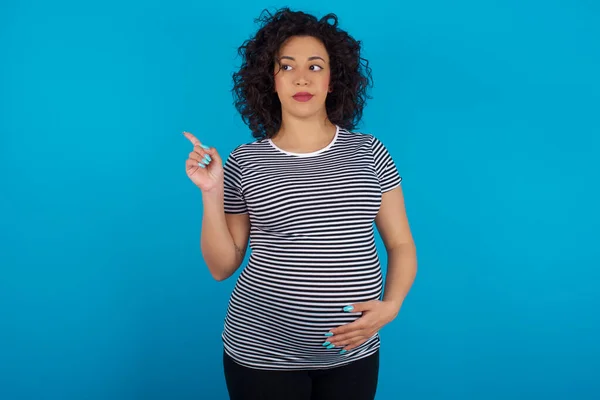 Schwangere Araberin Mit Gestreiftem Shirt Zeigt Auf Kopierplatz Und Wirbt — Stockfoto