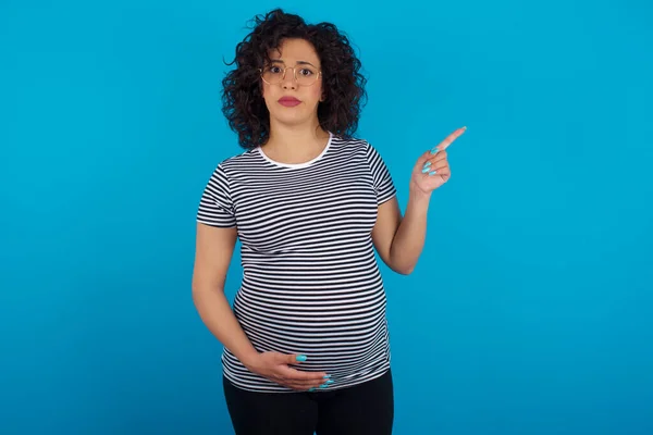 Ernsthaft Schwangere Arabische Frau Gestreiften Shirt Grinst Gesicht Zeigt Weg — Stockfoto